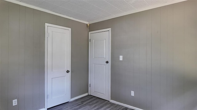 617 Holman Pl, Midwest City, OK 73110 - unfurnished bedroom featuring wood finished floors, crown molding, wood walls, and baseboards