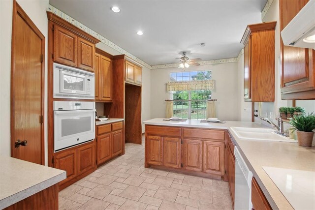 1227 Stout Dr NW, Piedmont, OK 73078 - kitchen featuring white appliances, light countertops, a sink, brown cabinetry, and a peninsula