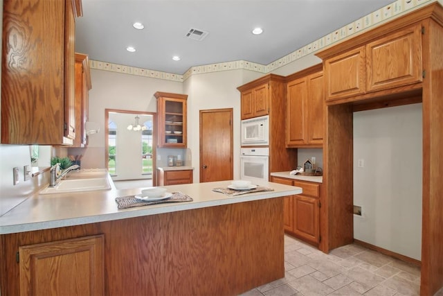 1227 Stout Dr NW, Piedmont, OK 73078 - kitchen with a sink, white appliances, a peninsula, light countertops, and brown cabinetry