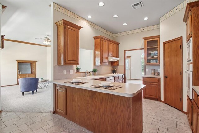 1227 Stout Dr NW, Piedmont, OK 73078 - kitchen featuring a sink, under cabinet range hood, light countertops, brown cabinets, and recessed lighting