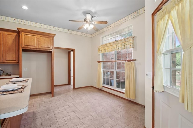1227 Stout Dr NW, Piedmont, OK 73078 - kitchen with stone finish flooring, a ceiling fan, brown cabinets, light countertops, and baseboards