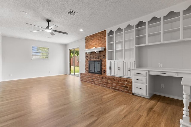 6 Utah Ave, Yukon, OK 73099 - unfurnished living room with light wood-style flooring, a textured ceiling, ceiling fan, a fireplace, and baseboards