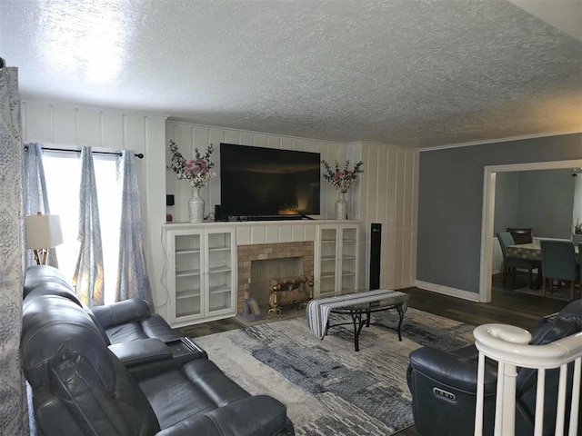 915 NW Euclid Ave, Lawton, OK 73507 - living room featuring wood finished floors, a textured ceiling, a fireplace with raised hearth, baseboards, and ornamental molding