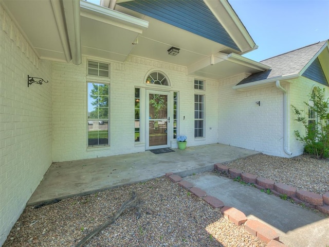 1900 New Haven Ct, Moore, OK 73160 - view of exterior entry featuring brick siding, roof with shingles, and a patio area
