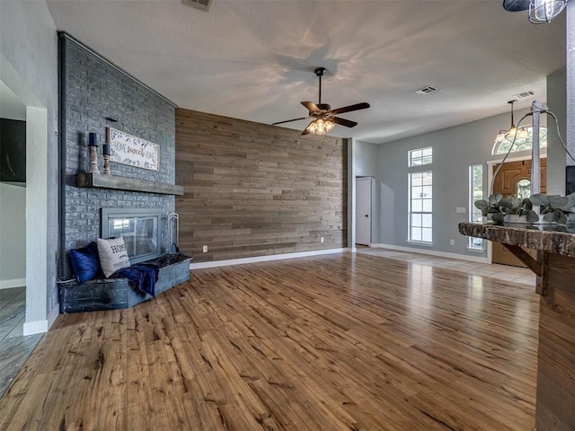 1900 New Haven Ct, Moore, OK 73160 - unfurnished living room featuring a fireplace, wood finished floors, ceiling fan, baseboards, and wood walls