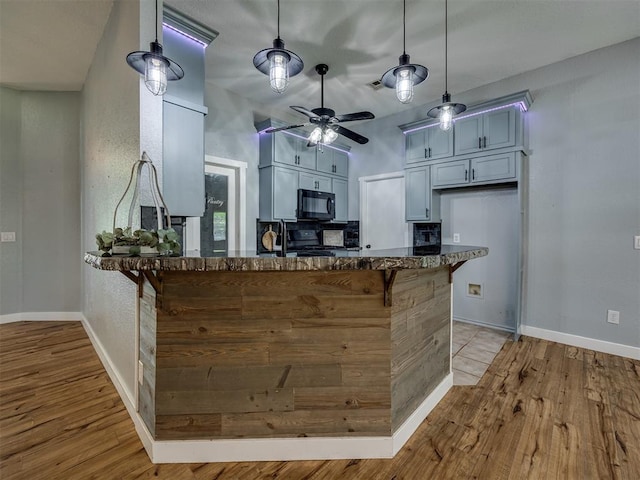 1900 New Haven Ct, Moore, OK 73160 - kitchen with black microwave, gas range, baseboards, and a peninsula