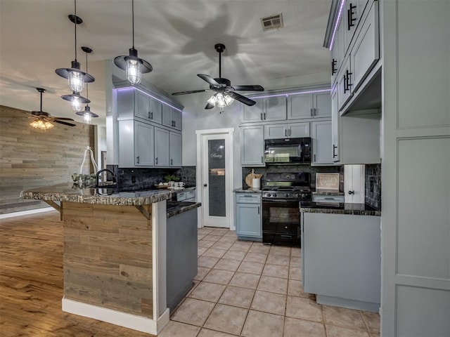 1900 New Haven Ct, Moore, OK 73160 - kitchen featuring black appliances, a ceiling fan, a peninsula, tasteful backsplash, and wooden walls