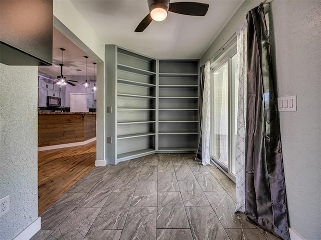 1900 New Haven Ct, Moore, OK 73160 - empty room featuring a ceiling fan, built in shelves, a textured wall, and marble look tile flooring
