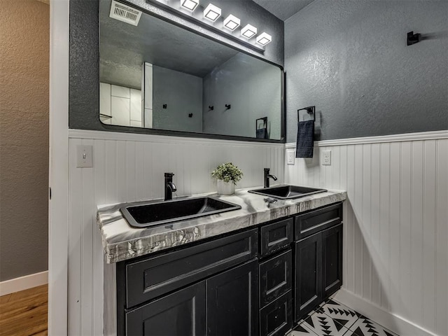 1900 New Haven Ct, Moore, OK 73160 - full bathroom with a wainscoted wall, double vanity, a textured wall, baseboards, and wood finished floors