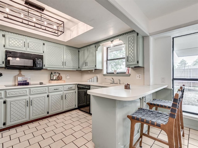 209 E Platt Dr, Yukon, OK 73099 - kitchen featuring black appliances, a sink, a peninsula, a breakfast bar area, and light countertops