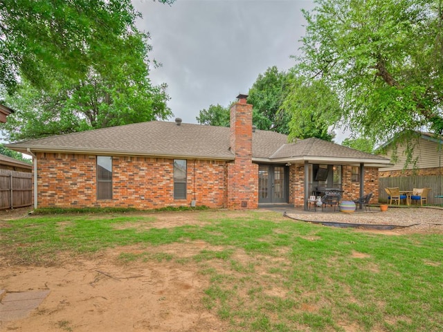 209 E Platt Dr, Yukon, OK 73099 - back of property featuring french doors, a chimney, a patio, a shingled roof, and brick siding