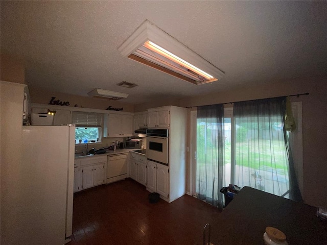 617 Mark Dr, Oklahoma City, OK 73115 - kitchen with white appliances, white cabinetry, dark wood-style floors, light countertops, and a sink