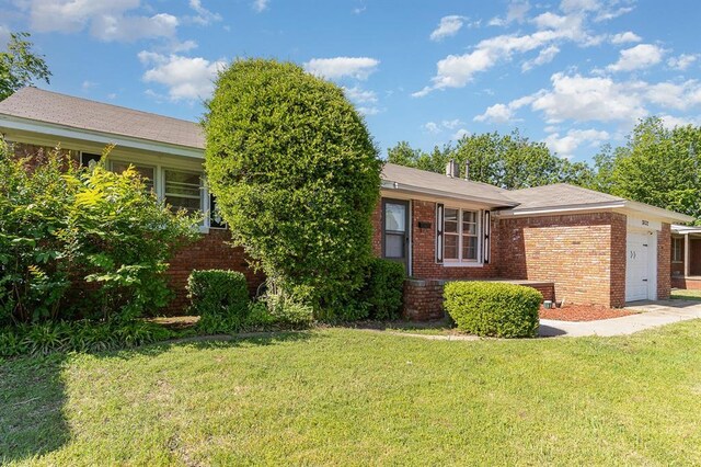 3032 NW 67th St, Oklahoma City, OK 73116 - view of front facade with an attached garage, brick siding, and a front yard