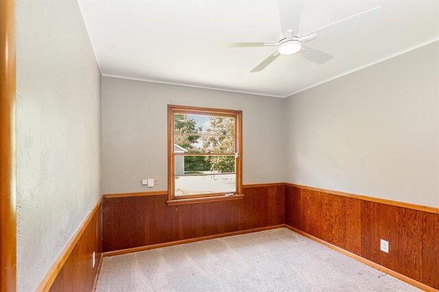 3032 NW 67th St, Oklahoma City, OK 73116 - empty room featuring wainscoting, wooden walls, light carpet, and ceiling fan