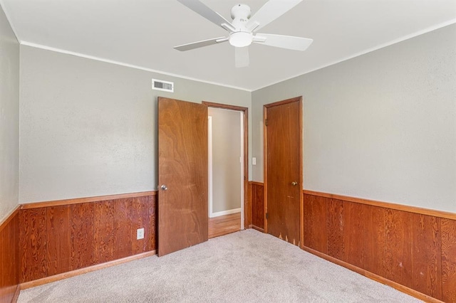 3032 NW 67th St, Oklahoma City, OK 73116 - unfurnished room featuring a wainscoted wall, a ceiling fan, wooden walls, and carpet