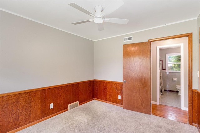 3032 NW 67th St, Oklahoma City, OK 73116 - carpeted empty room featuring ceiling fan, a wainscoted wall, ornamental molding, and wood walls
