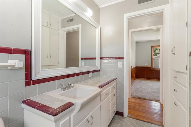 3032 NW 67th St, Oklahoma City, OK 73116 - bathroom featuring wainscoting, tile walls, vanity, and wood finished floors