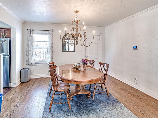 705 Chautauqua Ave, Norman, OK 73069 - dining area featuring light wood-type flooring, a chandelier, a textured ceiling, baseboards, and crown molding