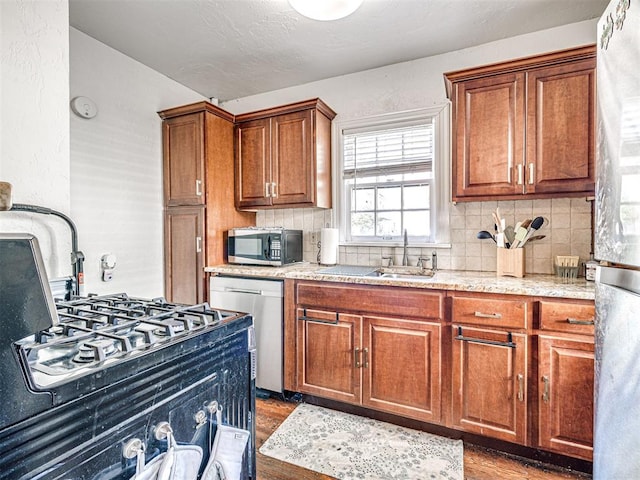 705 Chautauqua Ave, Norman, OK 73069 - kitchen featuring stainless steel appliances, brown cabinets, wood finished floors, a sink, and tasteful backsplash