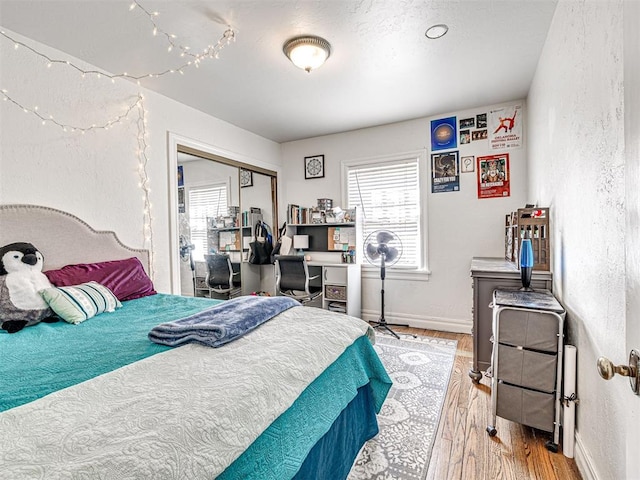 705 Chautauqua Ave, Norman, OK 73069 - bedroom with wood finished floors, a textured wall, a closet, baseboards, and a desk