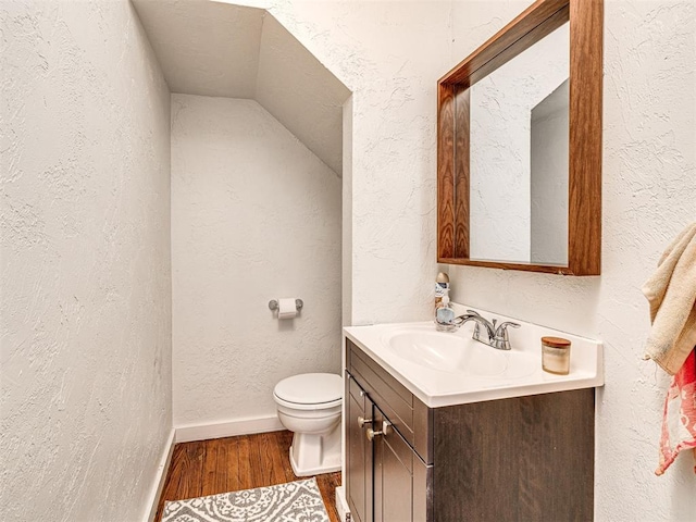 705 Chautauqua Ave, Norman, OK 73069 - half bath featuring vanity, wood finished floors, toilet, a textured wall, and baseboards