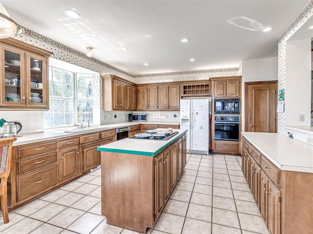2616 Redvine Rd, Edmond, OK 73034 - kitchen featuring black appliances, a kitchen island, a sink, light countertops, and backsplash