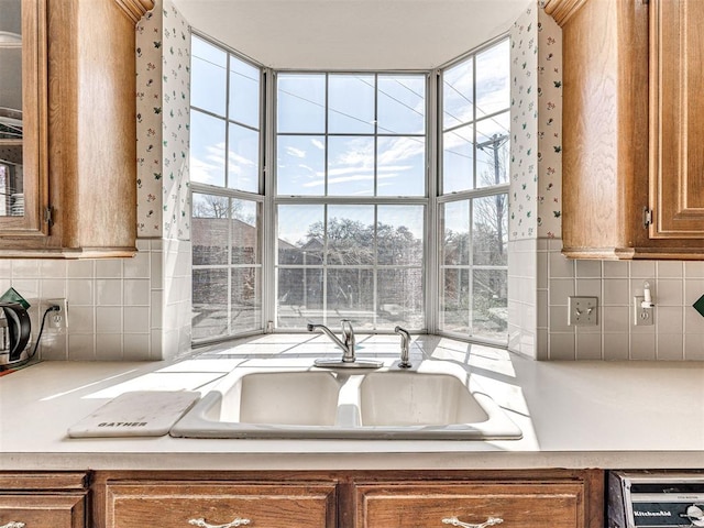 2616 Redvine Rd, Edmond, OK 73034 - kitchen featuring brown cabinetry, a sink, backsplash, light countertops, and healthy amount of natural light