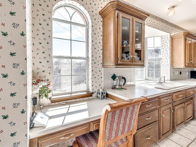 2616 Redvine Rd, Edmond, OK 73034 - kitchen with wallpapered walls, a sink, plenty of natural light, brown cabinets, and tasteful backsplash