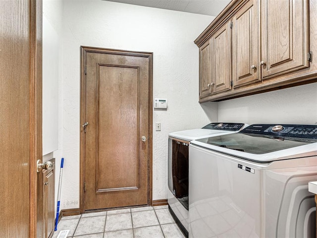 2616 Redvine Rd, Edmond, OK 73034 - laundry room featuring washing machine and dryer, baseboards, cabinet space, light tile patterned floors, and a textured wall