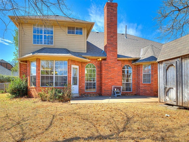 2616 Redvine Rd, Edmond, OK 73034 - back of property featuring a patio area, a shingled roof, brick siding, and a chimney