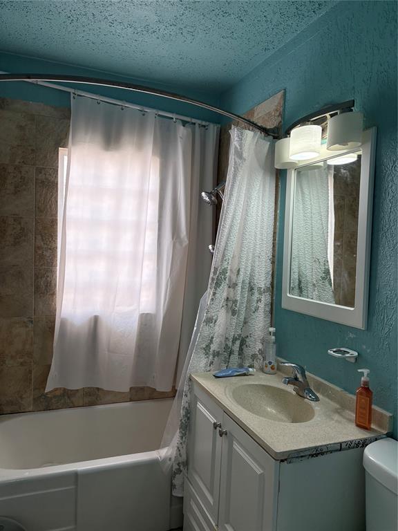 2508 N Cummings Dr, Oklahoma City, OK 73107 - full bathroom with vanity, shower / bath combination with curtain, toilet, and a textured wall
