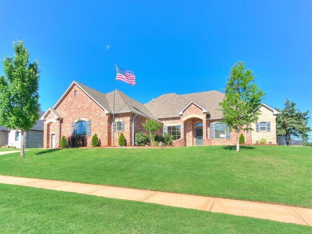 10716 Quail Reserve Rd, Oklahoma City, OK 73173 - view of front facade with brick siding, a front yard, and a shingled roof