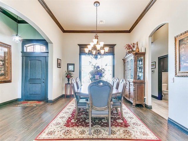 10716 Quail Reserve Rd, Oklahoma City, OK 73173 - dining space with a chandelier, wood finished floors, arched walkways, healthy amount of natural light, and ornamental molding