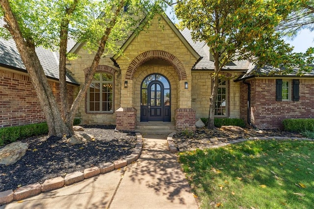 18617 Wolf Creek Dr, Edmond, OK 73012 - doorway to property featuring stone siding, brick siding, and roof with shingles