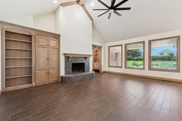 18617 Wolf Creek Dr, Edmond, OK 73012 - unfurnished living room with ceiling fan, high vaulted ceiling, beamed ceiling, a tiled fireplace, and dark wood-style flooring