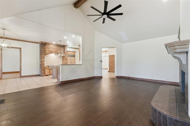 18617 Wolf Creek Dr, Edmond, OK 73012 - unfurnished living room featuring high vaulted ceiling, ceiling fan, a fireplace with raised hearth, beam ceiling, and wood finished floors
