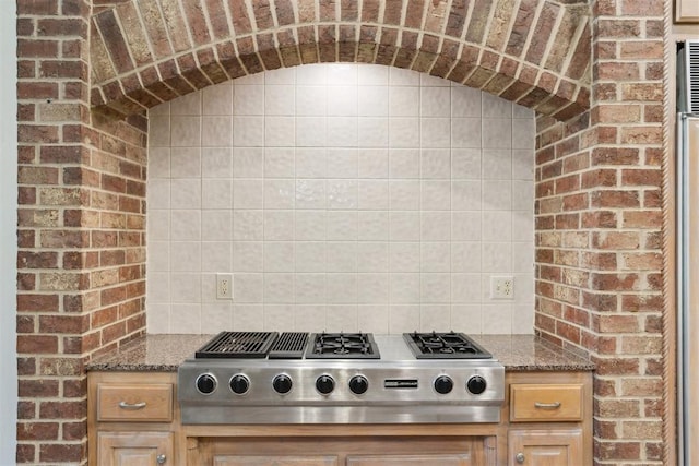 18617 Wolf Creek Dr, Edmond, OK 73012 - kitchen with stainless steel gas cooktop, stone countertops, brick wall, and backsplash
