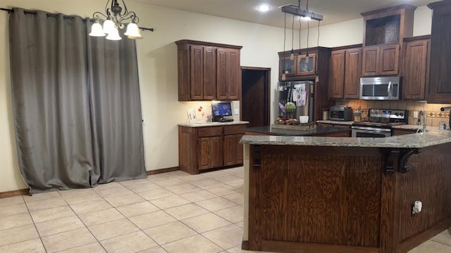928 County St Unit 2932, Tuttle, OK 73089 - kitchen with stainless steel appliances, a chandelier, a kitchen bar, light stone countertops, and hanging light fixtures