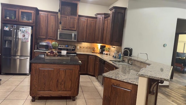 928 County St Unit 2932, Tuttle, OK 73089 - kitchen with appliances with stainless steel finishes, a peninsula, light stone countertops, light tile patterned floors, and backsplash