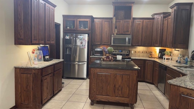 928 County St Unit 2932, Tuttle, OK 73089 - kitchen with stainless steel appliances, light tile patterned flooring, backsplash, a kitchen island, and light stone counters