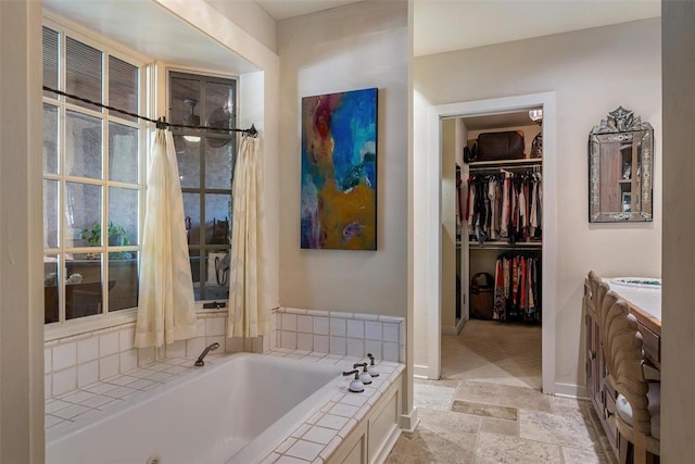 6638 Avondale Dr, Nichols Hills, OK 73116 - bathroom with a tub with jets, stone tile floors, vanity, a walk in closet, and baseboards