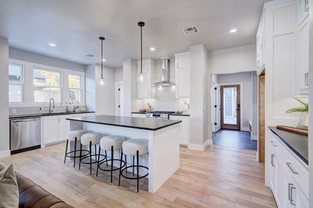108 NW 25th St, Oklahoma City, OK 73103 - kitchen featuring stainless steel appliances, wall chimney exhaust hood, a sink, dark countertops, and recessed lighting