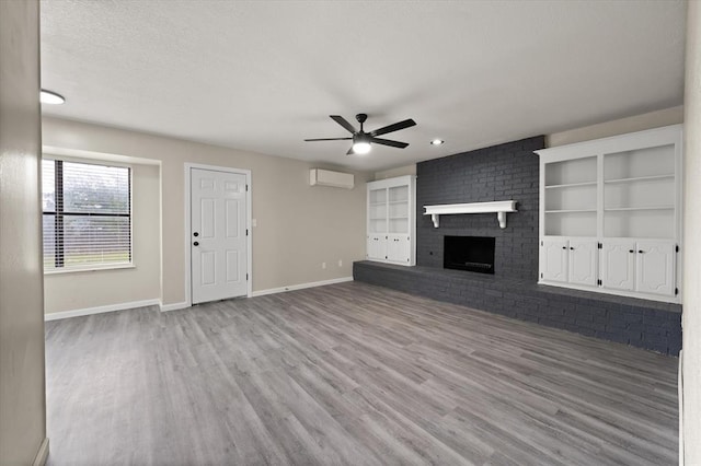 7 Concord Blvd, Shawnee, OK 74804 - unfurnished living room with a ceiling fan, wood finished floors, a wall unit AC, and baseboards