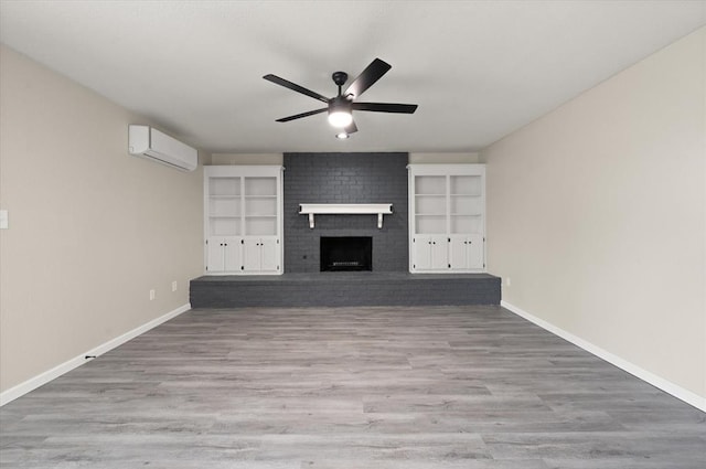 7 Concord Blvd, Shawnee, OK 74804 - unfurnished living room featuring a ceiling fan, a wall unit AC, a brick fireplace, baseboards, and wood finished floors