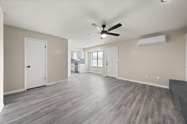 7 Concord Blvd, Shawnee, OK 74804 - unfurnished living room featuring a wall mounted AC, ceiling fan, wood finished floors, baseboards, and a textured ceiling