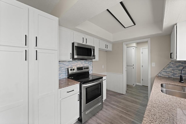 7 Concord Blvd, Shawnee, OK 74804 - kitchen with appliances with stainless steel finishes, a sink, light wood-style floors, white cabinetry, and wainscoting