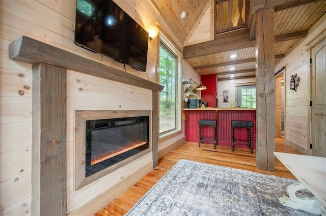21 Sherwood Forest Ln, Broken Bow, OK 74728 - living room with wooden ceiling, wood walls, a bar, a glass covered fireplace, and wood finished floors