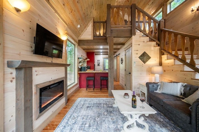 21 Sherwood Forest Ln, Broken Bow, OK 74728 - living room with stairs, wooden walls, wood finished floors, a glass covered fireplace, and wood ceiling