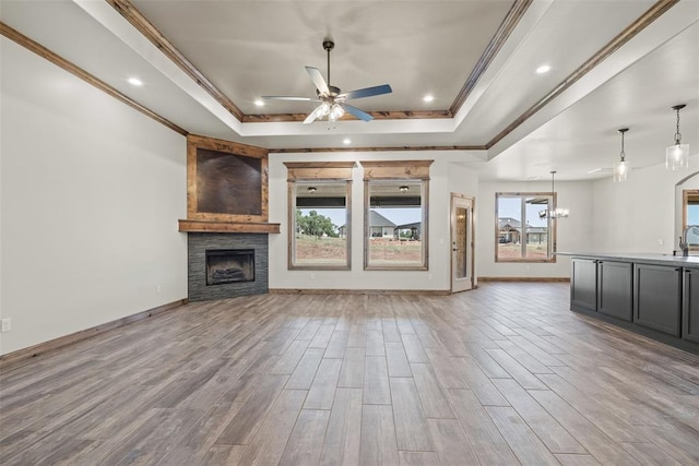 2414 Black Jack Way, Blanchard, OK 73010 - unfurnished living room with a raised ceiling, ceiling fan, a stone fireplace, wood finished floors, and a chandelier