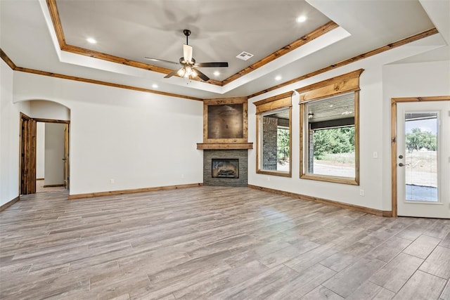 2414 Black Jack Way, Blanchard, OK 73010 - unfurnished living room featuring a raised ceiling, ornamental molding, light wood-style floors, a ceiling fan, and a stone fireplace